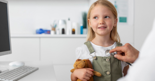 Doktor stetoskopom preslušava devojčicu koja drži plišanog medu