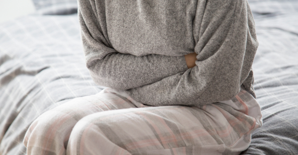 Žena u džemperu se drži za stomak zbog upale bešike